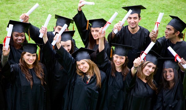 Graduates in caps and gowns holding rolled diplomas